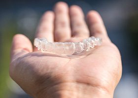 Invisalign tray sitting on man’s hand