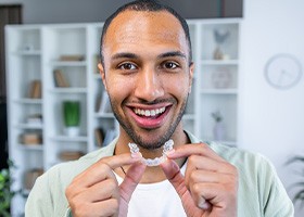 Smiling man holding Invisalign aligner