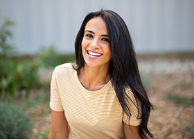 Woman with long, dark hair smiling outside