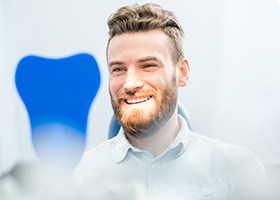 Man smiling in dental office looking at mirror