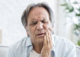 Man holding jaw in pain