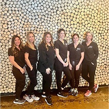 Dental team members smiling and standing against wall