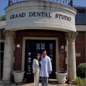 A man and woman stand together in front of a grand dental studio, showcasing a professional dental environment.