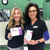 Two women in dental office holding boxes for dental products