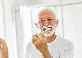older man brushing teeth 