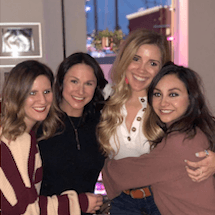 Four women smiling and hugging