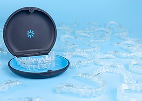 a bunch of Invisalign aligners on blue background with one set in carrying case
