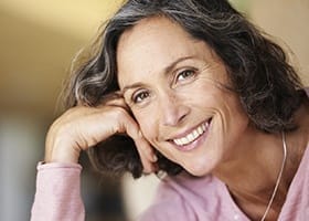 Older woman smiling and resting her cheek in her hand