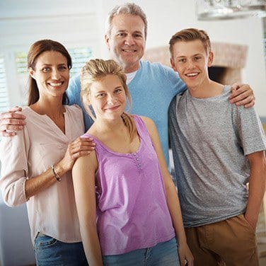 Family of four smiling in their living room after dental services in Oklahoma City