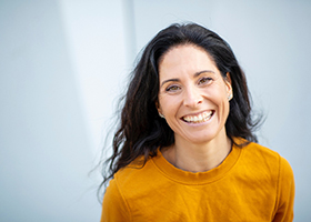 woman with long brown hair and orange shirt smiling