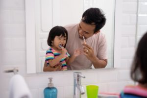 happy father and daughter brushing together 