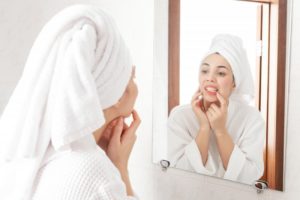 woman looking at teeth in the mirror 