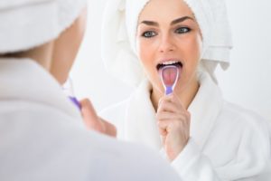 woman in bathrobe cleaning tongue 