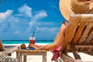 woman relaxing with drink on the beach